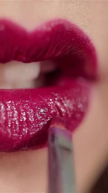 Bu çarpıcı yakın plan, güzel bir kadının nefis, kırmızı dudaklarını gösteren esmer bir kadınla güzelliğin özünü yakalıyor. Işıltılı son, onun pırıl pırıl gülüşünü vurguluyor, özgüven ve zarafet saçarak el değmemiş bir stüdyo arkaplanına.