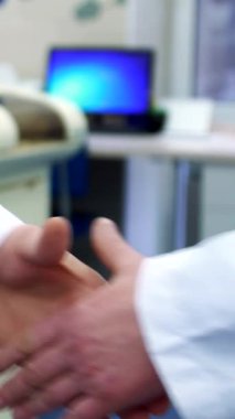 Saf beyaz önlüklü kendini adamış bir bilim adamı sıkı bir tokalaşmadan sonra ellerini uzatarak çığır açan bir araştırmaya hazır olduğunun sinyalini veriyor. Ellerinin yakın çekimi, birbirine masaj yapması, beklenti ve işbirliği yaratıyor.