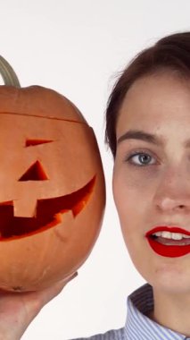 Kırmızı dudaklı hoş bir kadın, Cadılar Bayramı 'nda oyulmuş bir balkabağına sarılıp neşeli bir neşe saçıyor. Balkabaklarının sıcak parıltısı onun etkileyici özelliklerini güzel bir şekilde ön plana çıkarıyor, davetkar bir atmosfer yaratıyor.