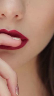 Kırmızıya vuran dudakları olan, parmağını hafifçe okşayan genç bir kızın büyüleyici yakın çekimi. Bu büyüleyici portre, onun kusursuz cildini ve büyüleyici bakışlarını vurguluyor. Zengin, siyah bir arkaplan, ışıldayan bir güzellik ve...