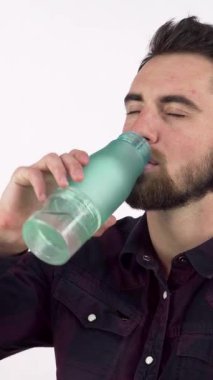 Bakımlı sakallı yakışıklı bir adam parlak, sulu bir şişeden serinletici bir yudum alır, sağlık ve zindelik saçar. Düşünceli ifadesi ve neşeli tavırları, sağlığını arttırmak için mükemmel bir ortam yaratıyor.