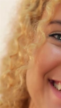 Işıltılı kıvırcık saçlı, ışıl ışıl, dişlek gülüşlü, saf neşe ve pozitiflik saçan göz kamaştırıcı bir kadın. Parlak cildi ve ışıl ışıl gözleri davetkar bir atmosfer yaratıyor. Gösterişli bir güzellik, kendine güven ve canlı bir hava yaratıyor.