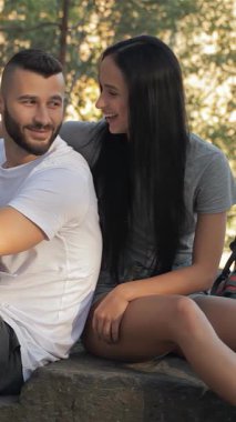 Canlı bir çift, yemyeşil bir ormanda, güneşli bir kayanın üzerinde oturur. Canlandırıcı sohbete dalarken neşe saçar. Esmer kadın elini nazikçe erkek arkadaşının omzuna koyar, o da başparmağını kaldırarak maceranın ruhunu somutlaştırır.