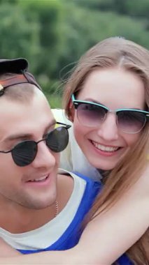 Neşeli genç bir adam şık arkadaşlarının güzel bir günün güneşinde güneşlenirken fotoğraflarını neşeyle çeker. Gülüşleri ve neşeli pozları, neşeli bir atmosfer yayıyor, arkadaşlığı ve unutulmaz anıları kutluyorlar.