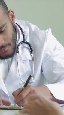 Parlak ve modern bir klinikte, kendini adamış bir doktor, sıcak ve destekleyici bir atmosfer sergileyerek, reçete yazarken hastasını dikkatle dinler. Çok ırklı sağlık uzmanları güven ve merhameti somutlaştırarak hayati önem taşıyorlar.