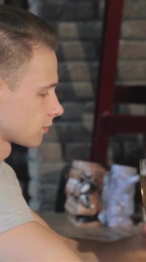 Şık, genç, beyaz bir adam şık bir barda serinletici uzun bir bardak altın biranın tadını çıkarıyor. Rahatlamış tavrı neşe saçıyor. Kırsal tuğla bir duvar ve yumuşak ışıklıklarla vurgulanan davetkar ortam, gevşemek için mükemmel bir sahne hazırlıyor.