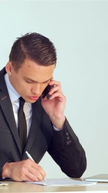 Gösterişli siyah takım elbiseli kendini işine adamış genç bir işadamı, bir telefon görüşmesi yaparken şık bir not defterine tutkulu bir şekilde notlar yazıyor. Dizüstü bilgisayar ve tabletin yer aldığı modern çalışma alanı profesyonellik ve üretkenlik yayarak,