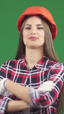 Canlı ve genç bir kadın inşaat işçisi, parlak bir ekose gömlek ve parlak yeşil renkli bir arka plana karşı koruyucu turuncu bir başlık giyerek güven içinde duruyor. Işıl ışıl gülüşü ve dengeli tavrı güçlenmeyi ve...