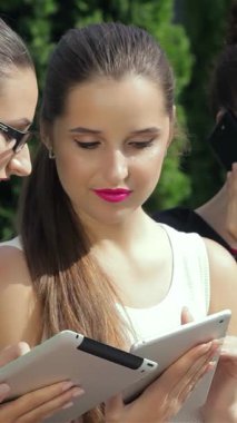 Üç şık iş kadını dışarıda işbirlikçi bir tartışmayla derinden ilgileniyorlar, biri kamerayla güven içinde göz teması kuruyor. Şık kıyafetleri ve canlı ifadeleri profesyonellik ve yakınlık yayıyor.