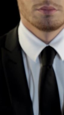 Pürüzsüz siyah takım elbiseli ve beyaz gömlekli genç beyaz bir adam dramatik bir siyah arka plana karşı cesurca duruyor ve şiddetli bir meydan okuma jesti ile yumruğunu kaldırıyor. Onun engebeli, tıraşsız yüzü ve delici bakışları yoğun bir atmosfer yayıyor.