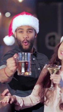 Coşkulu, çoklu etnik arkadaşlardan oluşan, Noel Baba şapkalı neşeli bir grup bardaklarını coşkulu bir şekilde kaldırıyorlar. En sevdikleri futbol takımını kutlarken elektrik atmosferi kahkaha ve tezahüratla uğulduyor.