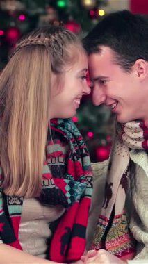 Sıcak kazaklar ve canlı eşarplarla sarılı neşeli bir çift, sıcak dekore edilmiş bir odada güzel paketlenmiş Noel hediyelerini paylaşırken hassas anları paylaşıyor. Göz kamaştıran ışıklar ve göz kamaştırıcı bir Noel 'le aydınlatılan büyüleyici bir ortam.