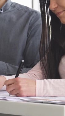 Yakın plan bir fotoğraf şık pembe bluzlu bir kadını yakalar, profesyonel bir satıcı ona canlı bir araba galerisinde yardım etmek için hazır beklerken önemli belgeleri imzalar. Bu dinamik sahne yeni bir araç almanın heyecanını yayıyor.