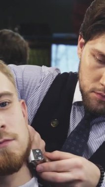 Büyüleyici bir klasik berber dükkanında, yetenekli bir berber zarif genç bir adamın sakalını dikkatlice kesiyor, sıcak, davetkar bir aydınlatmayla kaplıyor. Bu samimi an berberlerin sanatsallığını ve hassasiyetini ön plana çıkarıyor. Müşterileri rahatlatıyor.