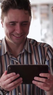 Sıcak ve davetkar bir kafede, iki genç adam bir tableti incelerken önemli haberleri tartışırken duygusal bir an paylaşıyorlar. İfadeleri, şaşkınlık ve endişe karışımı büyüleyici bir atmosfer yaratıyor.