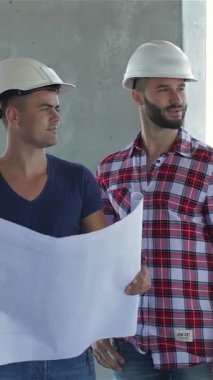 Sert şapkalı üç inşaatçı canlı bir inşaat sahasında gururla duruyor, yoldaşlık ve hırs yayıyorlar. Merkezdeki Kafkasyalı adamın elinde damalı gömlekli iki şık giyimli işçi tarafından çevrelenmiş ayrıntılı bir plan var.