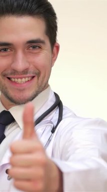 Gıcır gıcır beyaz bir tıp elbisesi içinde kendine güvenen genç bir erkek doktor olumlu ve profesyonellik saçıyor. Boynunda zarif bir steteskop ve sıcak, davetkar bir gülümsemeyle sağlık hizmetinin ruhunu somutlaştırıyor.