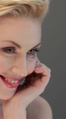 Işıl ışıl bir teni ve nazik bir gülüşü olan büyüleyici bir kadın yumuşak, gri bir arkaplana karşı güven yayar. Onun narin hatları ve şık sarı saçları büyüleyici bir portre oluşturuyor. Bu, sonsuz güzellik ve zarafeti temsil ediyor.