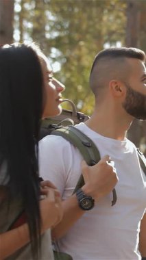 Maceraperest bir erkek yürüyüşçü canlı yeşil bir ormanın içinden güvenli bir şekilde yolu gösterirken çarpıcı bir esmer kız arkadaşı hayranlıkla ona bakıyor. Sırt çantaları, aşk ve keşif ruhunu somutlaştıran ortak bir yolculuğa işaret ediyor.