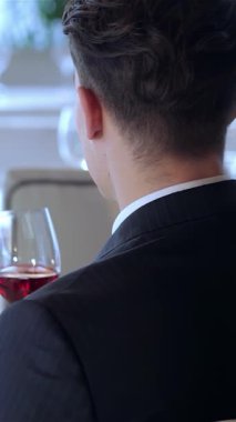 Lezzetli genç bir çift romantik bir anı paylaşıyor. Kadehlerinde zengin kırmızı şarap kadehlerini kaldırırken lüks restoranın zarif atmosferi onları sarıyor. Yumuşak ışık ve narin güllerle çevrili neşeli ifadeleri