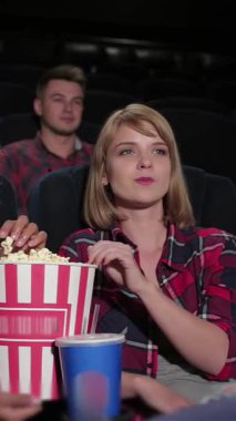 Canlı bir grup genç arkadaş, yüzleri neşe ve heyecanla aydınlanan sıcak bir sinemada büyüleyici bir filme daldı. Büyük boy patlamış mısır kovaları ve renkli içeceklerle, atmosfer kahkaha ve arkadaşlıkla uğulduyor.