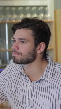 İki neşeli genç adam, biri şık sakallı, neşeli bir şekilde bardakta buzlu bira bardaklarıyla kadeh kaldırıyor. Kahkahaları ve enerjik enerjileri havayı dolduruyor, canlı bir bar atmosferinde hayat dolu anları kutluyor.