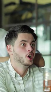 Heyecanla dolu canlı bir barda, buzlu bira bardaklarıyla kadeh kaldıran iki genç iş adamının yüzleri neşe ve dostluk saçıyordu. Canlı bir gülümseme ile bağıran bir arkadaş, onların tezahürat yaparken o anın heyecanını yakalar.