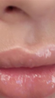 Bu büyüleyici makro görüntü, soluk pembe parlak dudakların büyüleyici cazibesini ve yumuşak stüdyo ışıklarının altında hafifçe parıldamasını sergiliyor. Mercek, enfes dudaklardan zarif bir şekilde Asyalı bir kadının huzurlu, kapalı gözüne doğru kayıyor.