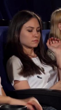 Neşeli ve ışıl ışıl gözleriyle genç bir kadın, arkadaşları sinemada patlamış mısırına dalarken şüpheyle izliyor. Canlı kırmızı-beyaz çizgili kova sönük, sıcak atmosfer karşısında patlar, bir kapsül