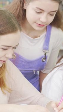 Üç şevkli genç kız renkli kitaplıklarla çevrili canlı bir kampüs kütüphanesinde ortak bir projeye daldılar. Bulaşıcı kahkahaları ve ortak fikirleri arkadaşlığın ve takım çalışmasının özünü yayıyor.