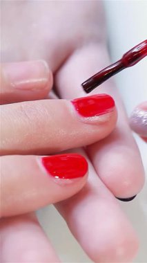 Zarif kadın elleri canlı kırmızı bir manikürle süslenmiş yumuşak, kremsi bir zemine karşı nazikçe dinleniyor. Bu yakın plan, oje sürmüş tırnakların ihtişamlı parıltısını ve pürüzsüzlüğün pürüzsüzlüğünü vurgulayarak, tırnak tasarımının sanatını güzel bir şekilde yakalıyor.