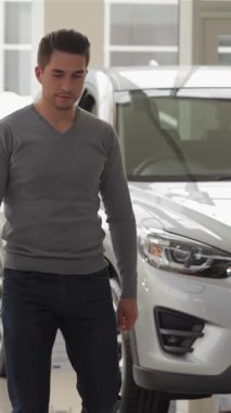 Modadan anlayan genç bir adam, modern bir otomobil galerisinde geziyor. Model arabaların göz kamaştırıcı gösterisinden büyüleniyor. Parlak, cilalı ambiyansı, bir sonraki heyecan verici alımını tasarlayan bir pazarlamacıyla etkileşime girerken heyecan saçıyor.