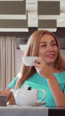 Enfes bir çift şık bir kafede sakin bir sabah çayından zevk alır. Samimi fısıltılarını paylaşırken gözleri sevgiyle parlar. Güzel kadın, dalgalı altın saçlarıyla, bardağını sallar, sıcaklık ve neşe saçar,