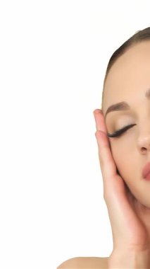 Bu zarif yakın plan beyaz bir kadının kusursuz tenini okşamasını, zarafet ve sükunet saçmasını içeriyor. Gözleri yavaşça kapalı ve huzurlu bir gülümseme ile kendine güveni ve güzelliği canlı beyaz bir arka plana karşı somutlaştırıyor.