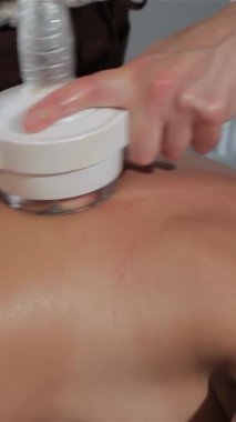 Uzman bir masör, yüksek teknolojili bir masaj aletini bir kadının kürek kemiğinin üzerinden ustalıkla geçirir ve rahatlamanın huzurlu bir vahasını yaratır. Cihaz pürüzsüz cildini okşarken rahatlatıcı, dairesel hareketleri yakalar ve gençleştirmeyi teşvik eder.