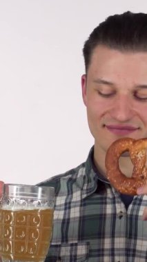 Neşeli genç bir adam, şık bir ekose gömlekle giyinmiş, köpüklü biranın tadını çıkarırken, sıcak, altın-kahverengi krakerin tadını çıkarıyor. Bu canlı sahne, Ekim Festivali 'nin neşeli atmosferini somutlaştıran kutlama ve eğlence ruhunu yansıtıyor.