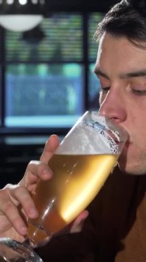 Yakışıklı genç bir adam altın zanaat birasından hoş bir yudum alır, barın sıcak atmosferine daldırır. Işıkların yumuşak parlaklığı ve davetkar atmosfer boş zamanı için mükemmel bir zemin oluşturur.