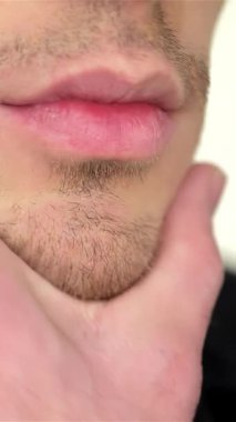 Cesur genç bir adam aynanın karşısında duruyor, tek eliyle nazikçe çenesini okşuyor, kendine güveni ve cazibesi yayılıyor. Tişörtsüz görünüşü, heykeltraş köpüğü figürlerini sergiliyor. Tıraş köpüğüne biraz neşe katıyor.