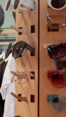 Dalgalı siyah saçlı neşeli bir kadın renkli kıyafetler ve moda aksesuarlarla dolu şık gözlüklerle deney yaparken neşe saçıyor. Bu dinamik sahne perakende terapisinin heyecanını özetliyor.