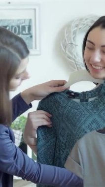 İki neşeli kız hevesle satıştaki moda elbiseleri seçiyor, kahkahaları canlı butikte yankılanıyor. Canlı atmosfer renkli kumaşlar ve şık seçeneklerle dolu. Alışveriş maceralarını keyifli bir deneyim haline getiriyor.