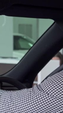 Neşeli bir adam, galeride lüks bir arabanın içinde rahatlarken, sevinçten havalara uçuyor. Bu dinamik sahne otomotiv sahipliğinin heyecanını özetliyor, modern enerjinin canlı enerjisini gösteriyor.