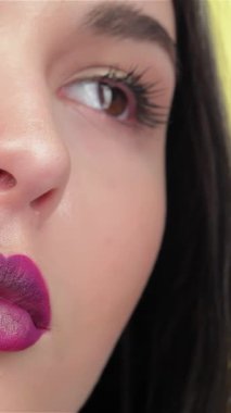 Yetenekli bir vizör, güzel bir esmer kızın dudaklarını ustalıkla güçlendirir. Erikli rujunu titizlikle sürerek. Parlak sarı arka plan sıcaklığı yansıtıyor. Bu muhteşem Asyalı kadının büyüleyici bakışlarını ve kusursuz bakışlarını vurguluyor.