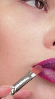 Yetenekli bir vizörcü, doğal cazibesini arttırmak için güzel bir esmer kızın dudaklarına canlı erik ruju sürüyormuş. Yumuşak sarı arka plan sıcaklığı yansıtıyor, Asyalı kadınların dikkatini çekiyor büyüleyici gözler ve kusursuz gözler.