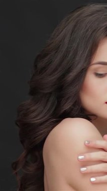 Çıplak omuzlu, kendine güvenen genç bir kadın kameraya baştan çıkarıcı bir şekilde bakıyor, çarpıcı kırmızı dudakları ve yumuşak kıvrımları, parlak siyah bir arka planda yüzünü çerçeveliyor. Bu büyüleyici portre zarafet ve entelektüellik yayıyor.