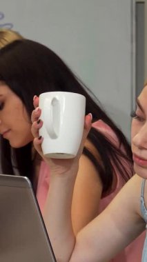 Yorgun ve genç bir iş kadını, elinde beyaz bir kahve fincanı tutarken, kendini adamış ekibiyle birlikte bir başlangıç projesinin baskısıyla uğraşırken derin bir iç çekiş veriyor. Hava gerginlik ve yaratıcılıkla dolu, işbirliğinin zorluklarını vurguluyor.