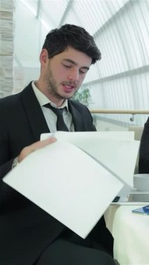 Doğal ışıkla dolu parlak, havadar bir ofiste dört dinamik işadamı, belgeler ve bir dizüstü bilgisayarla çevrili fikirlerini ve stratejilerini hevesle paylaşıyor. Bulaşıcı gülüşleri ve işbirlikçi ruhları bir atmosfer yaratıyor.