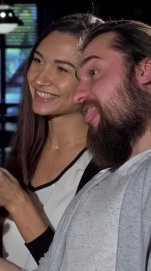 Sıcak ışıklandırmayla dolu rahat bir barda neşeli bir grup arkadaş neşeli selfie 'ler çeker kahkahaları bardakların tıkırtısıyla karışır. Yakışıklı adam, ışıl ışıl bir kadının yanında köpüklü bir içecek tutuyor.