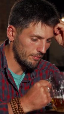 Olgun, sakallı bir adam, derin düşüncelere dalmışken, sıcak bir barda oturmuş, soğuk bir birayı kucaklıyor. Bar ışıklarının yumuşak, sıcak parıltısı yumuşak gölgeler bırakır, yalnızlık atmosferini ve yansıtıcı melankoliyi arttırır.