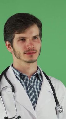 Işıl ışıl beyaz laboratuvar önlüğü giymiş ışıl ışıl genç bir erkek doktor dostça bir gülümseme, sıcaklık ve profesyonellik saçıyor. Boynuna zarif bir steteskop dolayarak canlı yeşil bir arka plana karşı durarak özünü somutlaştırıyor.