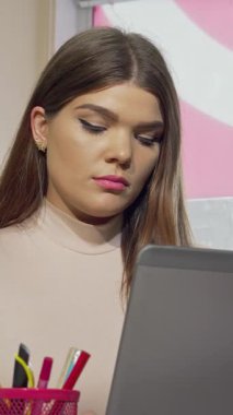 Uzun saçlı ve çarpıcı özellikleri olan kararlı bir kız öğrenci, masasında oturur, dizüstü bilgisayarında gezinirken hayal kırıklığı içinde şakaklarını ovuşturur. Yumuşak, sıcak ışık onun odaklanmış ifadesini vurguluyor, yoğun baskıyı somutlaştırıyor.